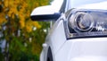 Car front view close-up on the background of a Park alley. Headlight glass. Background design. Detail of modern car headlights Royalty Free Stock Photo