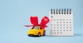 Car gift with red bow and calendar on blue background Royalty Free Stock Photo