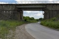 Car goes on asphalt road under the railway bridge Royalty Free Stock Photo