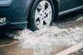 The car goes through a puddle. Puddles on the road. Water from the wheels. Road after the rain. . Russia, Leningrad region, Royalty Free Stock Photo