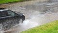 The car goes on the road in heavy rain, water sprays out under the wheels Royalty Free Stock Photo