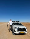 Car on gravel road in desert. Sandy landscape. Toyota Hilux. Man driver.