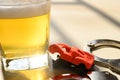 Car and handcuffs & cup of beer in jail close up concept of illegal drunk driving