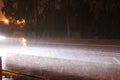 Car headlight illuminates rain in the dark on the track