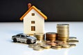 Car and house model with coins on white table. Saving money to buy own property. Loan and credit concept. Royalty Free Stock Photo