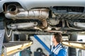 Car On Hydraulic Lift With Mechanic Working In Garage