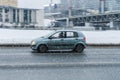 Car Hyundai Getz moving on slippy wet road in city street during snowfall in winter time
