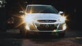 car Hyundai Solaris is parked on the street. Frontal view of silver auto with glowing headlamps