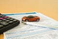 Car insurance concept with insurance form ,Miniature car, calculator and pen on a light wooden background