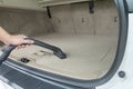 Car interior detailing vacuuming dust from a car carpet in the boot trunk