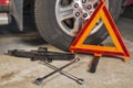 Car jack, lug wrench and safety triangle in a garage