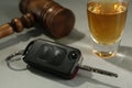 Car key, gavel near alcohol on table, closeup. Dangerous drinking and driving