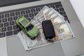 Car key and green toy car with money on a laptop keyboard Royalty Free Stock Photo