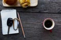 Car key on notepad with pencil and red coffee cup and bun bread on wood table backgrounds above Royalty Free Stock Photo