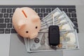 Car key and piggy bank with money on a laptop keyboard Royalty Free Stock Photo