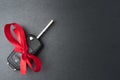 Car key with red bow on dark black slate plate Royalty Free Stock Photo