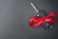 Car key with red bow on dark black slate plate Royalty Free Stock Photo