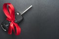 Car key with red bow on dark black slate plate Royalty Free Stock Photo