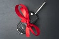 Car key with red bow on dark black slate plate Royalty Free Stock Photo