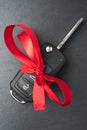 Car key with red bow on dark black slate plate Royalty Free Stock Photo