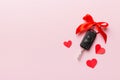 Car key with a red bow and a heart on Colored table. Giving present or gift for valentine day or christmas, Top view Royalty Free Stock Photo