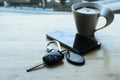 Car key and smartphone and coffee cup on wooden table Royalty Free Stock Photo