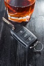 Car key and whiskey alcohol drink in a glass on black wooden table