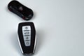 The car keys are black with metal inserts and automatic opening and closing buttons lying on the side on a white