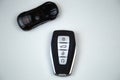 The car keys are black with metal inserts and automatic opening and closing buttons lying on the side on a white