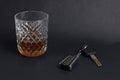 Car keys and glass with alcohol whiskey on black background, close-up