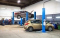 Car on lift in mechanic shop or garage, interior of auto repair workshop, vehicles inside maintenance Royalty Free Stock Photo