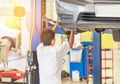 Car on lift to repair suspension in the garage with mechanic working underneath lifted car to change wheel hub Royalty Free Stock Photo