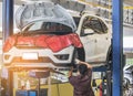 Car on lift to repair suspension in the garage with mechanics working underneath lifted car to change wheel hub and maintenance re Royalty Free Stock Photo