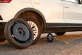 Car lifted by scissor jack and spare wheel on roadside