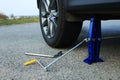 Car lifted by scissor jack without wheel outdoors, closeup. Tire puncture