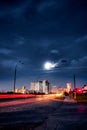 Car light trails in front of distant downtown buildings at summer night