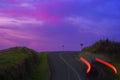 Car lights on mountain road with red sunset sky, Aiako Harriak Natural Park, Euskadi