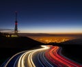 Car lights at night towards the city and communications antenna Royalty Free Stock Photo