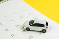 Car loan payment, buying new car or yearly maintenance schedule concept, miniature white car on clean calendar with date on yellow