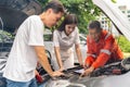 Car machanic showing the man and woman the problem of their car engine while parking on the side of a road