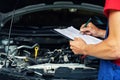 Car maintenance and repair - mechanic writing checklist paper on clipboard