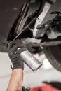Car master mechanic repairer lubricates screws with machine cleaner spray