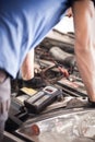 Car mechanic checking and testing automotive accumulator with battery tester Royalty Free Stock Photo