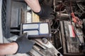 Car mechanic checking and testing automotive accumulator with battery tester Royalty Free Stock Photo