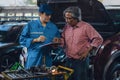 Car mechanic explaining to elder customer the maintenance list at garage and car maintenance service station Royalty Free Stock Photo