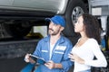 A car mechanic is explaining about the vehicle inspection. Mechanic worker explaining customer women about problems of her car