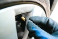 Car mechanic hand remove or close a tire valve cap of car wheel Royalty Free Stock Photo