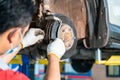 Car mechanic hands replace brakes in garage. Mechanic technician worker installing car wheel at maintenance. Worker changing brake Royalty Free Stock Photo