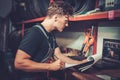 Car mechanic at his workplace preparing checklist in auto repair service.