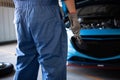 Car mechanic holding wrench for fixing to customer claim order in a auto repair garage workshop. Engine repair service. People Royalty Free Stock Photo